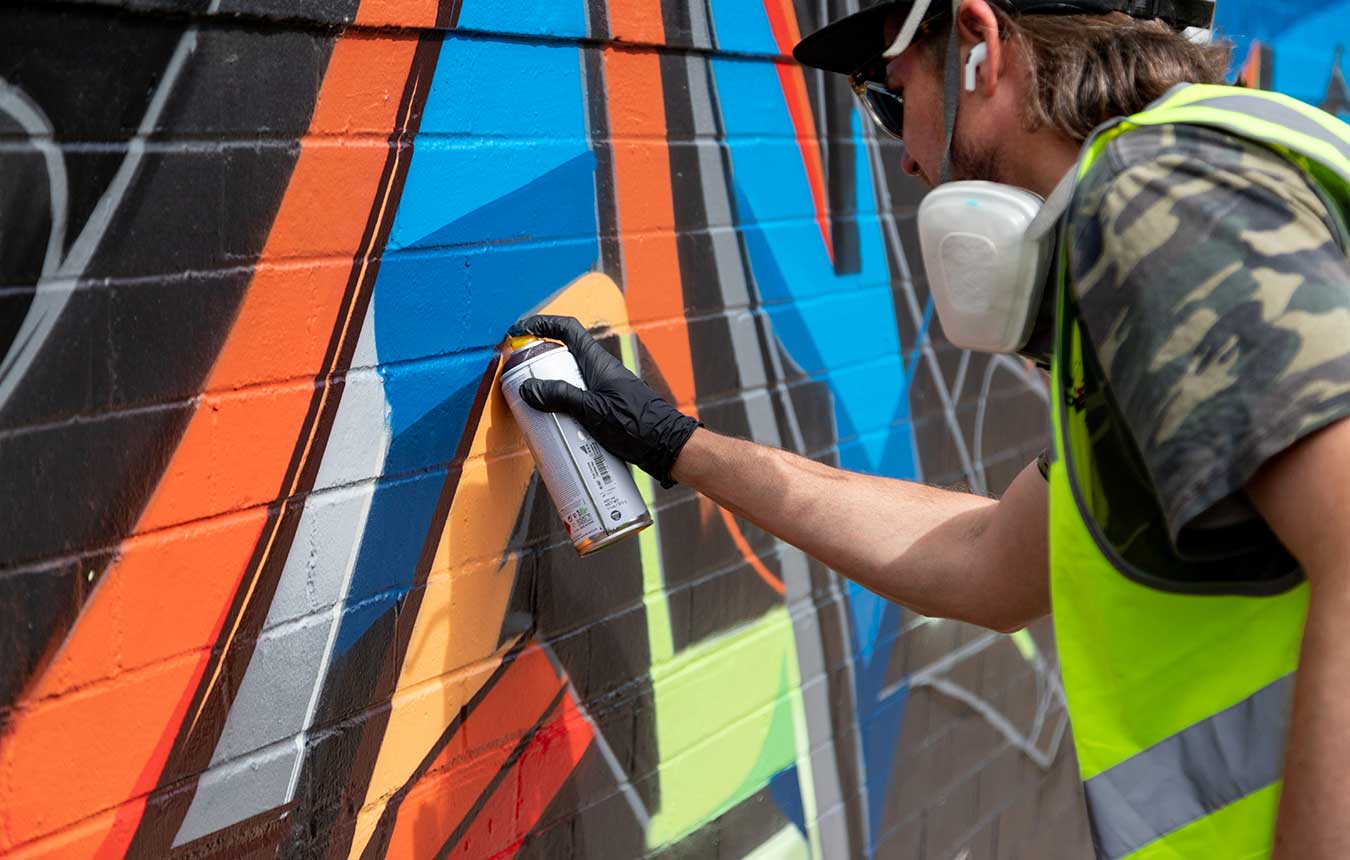 Vans the Omega spray painting a mural on the corner of Union and King Streets, Newcastle