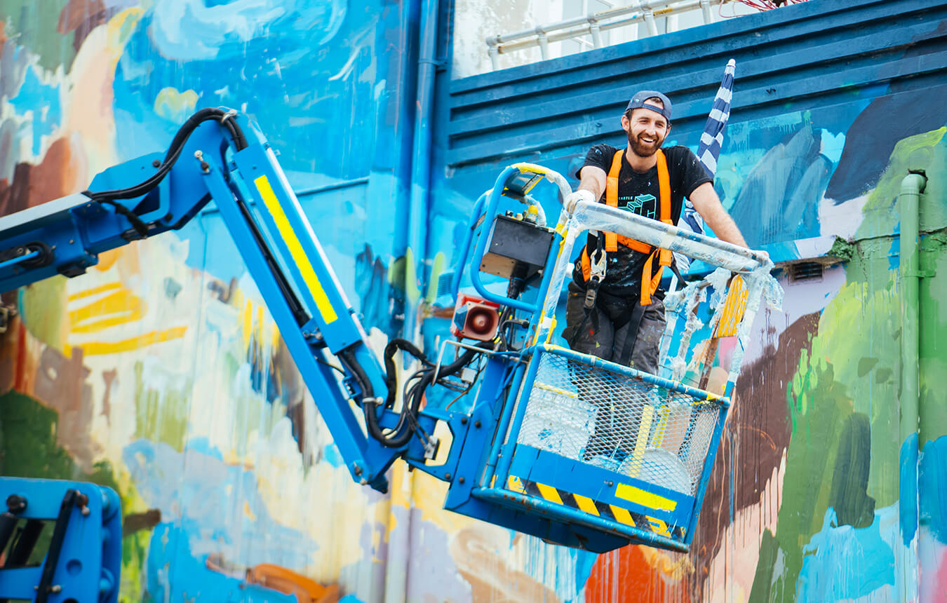 Michael Black in boom lift in front of mural in Gibson Street, Newcastle